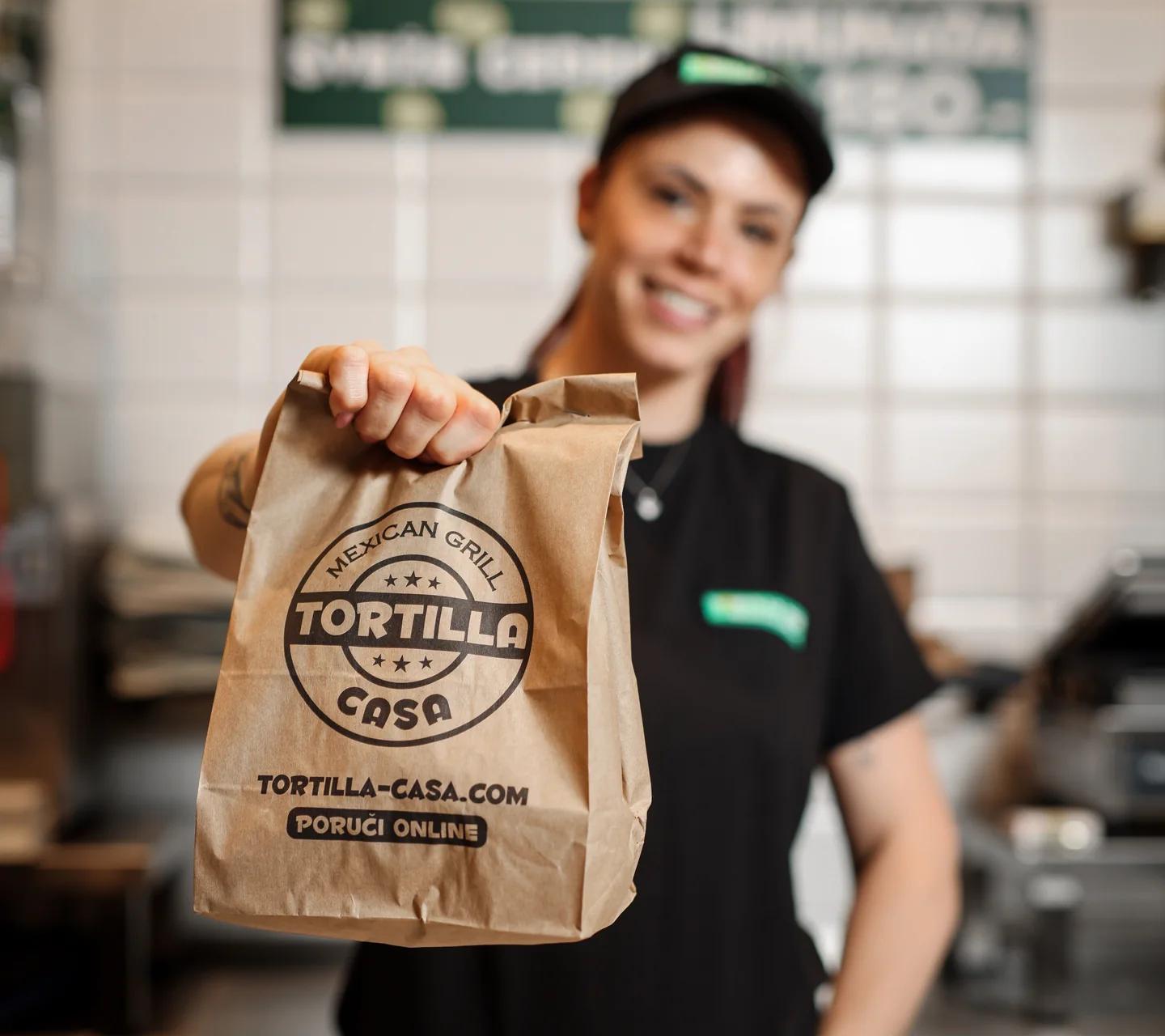 Koleginica iz Tortilla Casa restorana predaje papirnu kesu